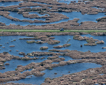 Aerial view of wetlands on Sherman Island, with a tractor parked on a levee, in part of the Sacramento-San Joaquin Delta.