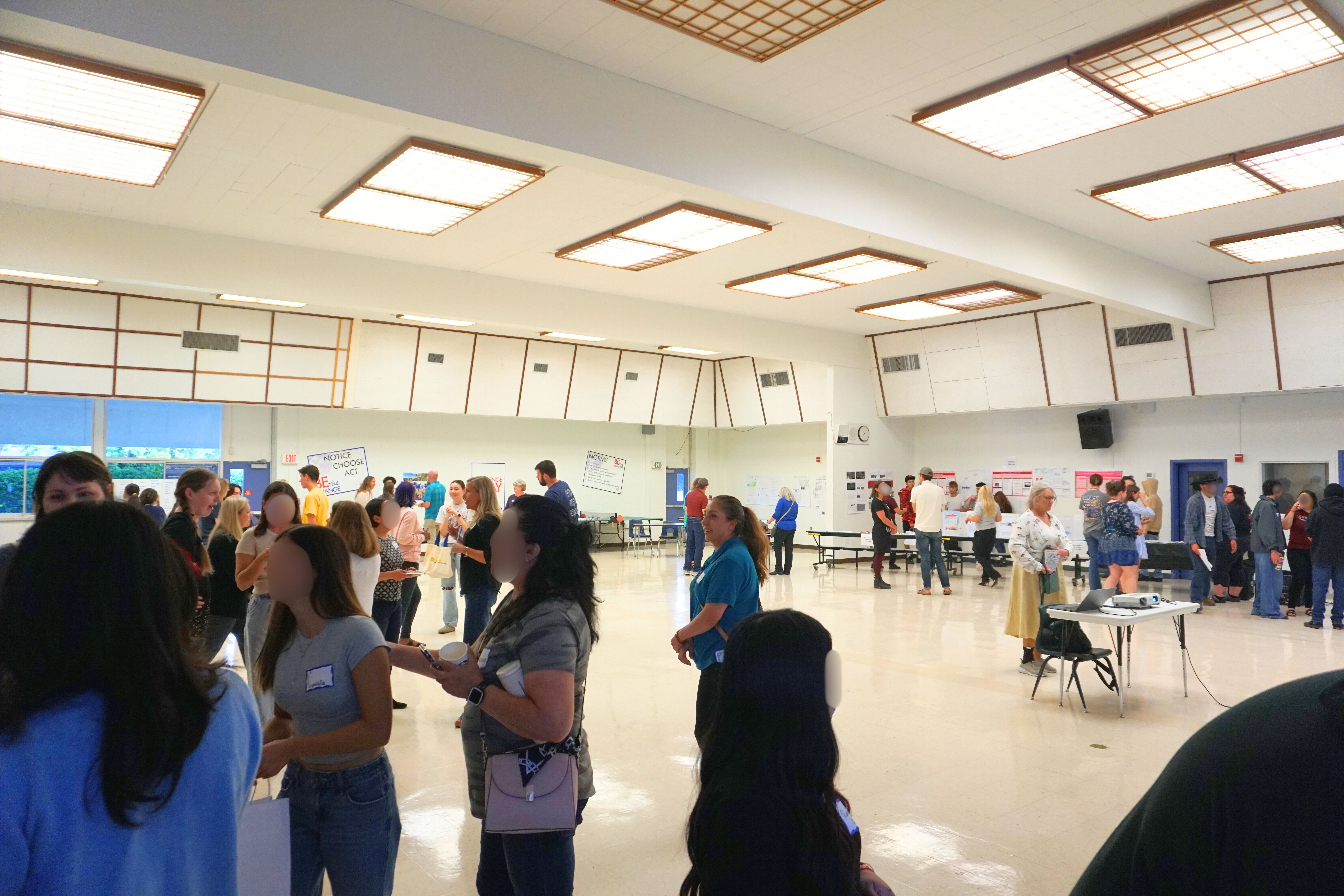 High school students presenting Spinning Salmon Program projects in an auditorium filled with teachers, families, and community members.
